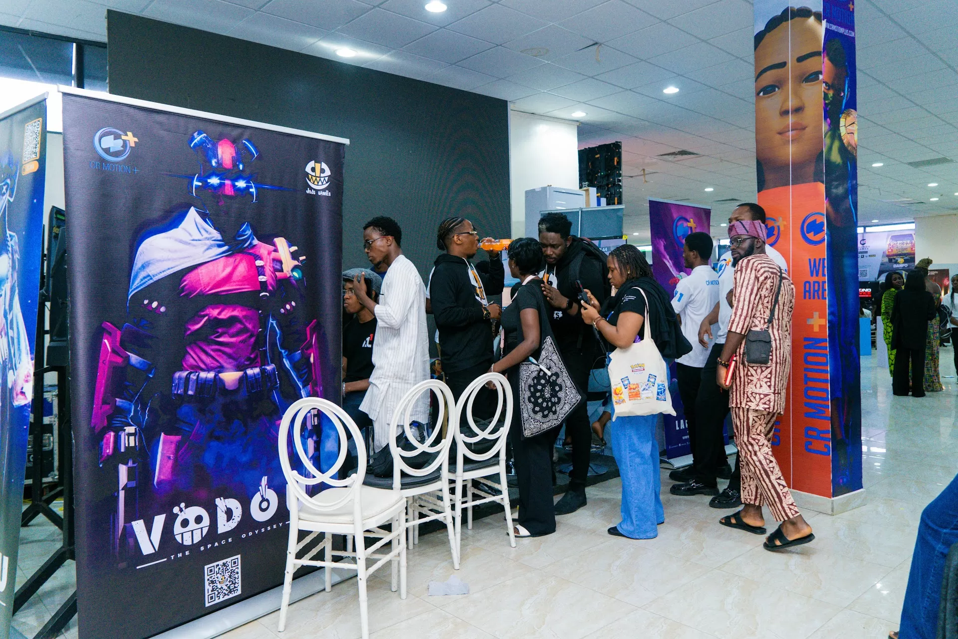 Africacomicade's Gamathon Returns to Lagos and Nairobi With a 'Back to Our Roots' Edition 4 Visitors at the Gamathon 2025 exhibition hall in Lagos beside a large game poster